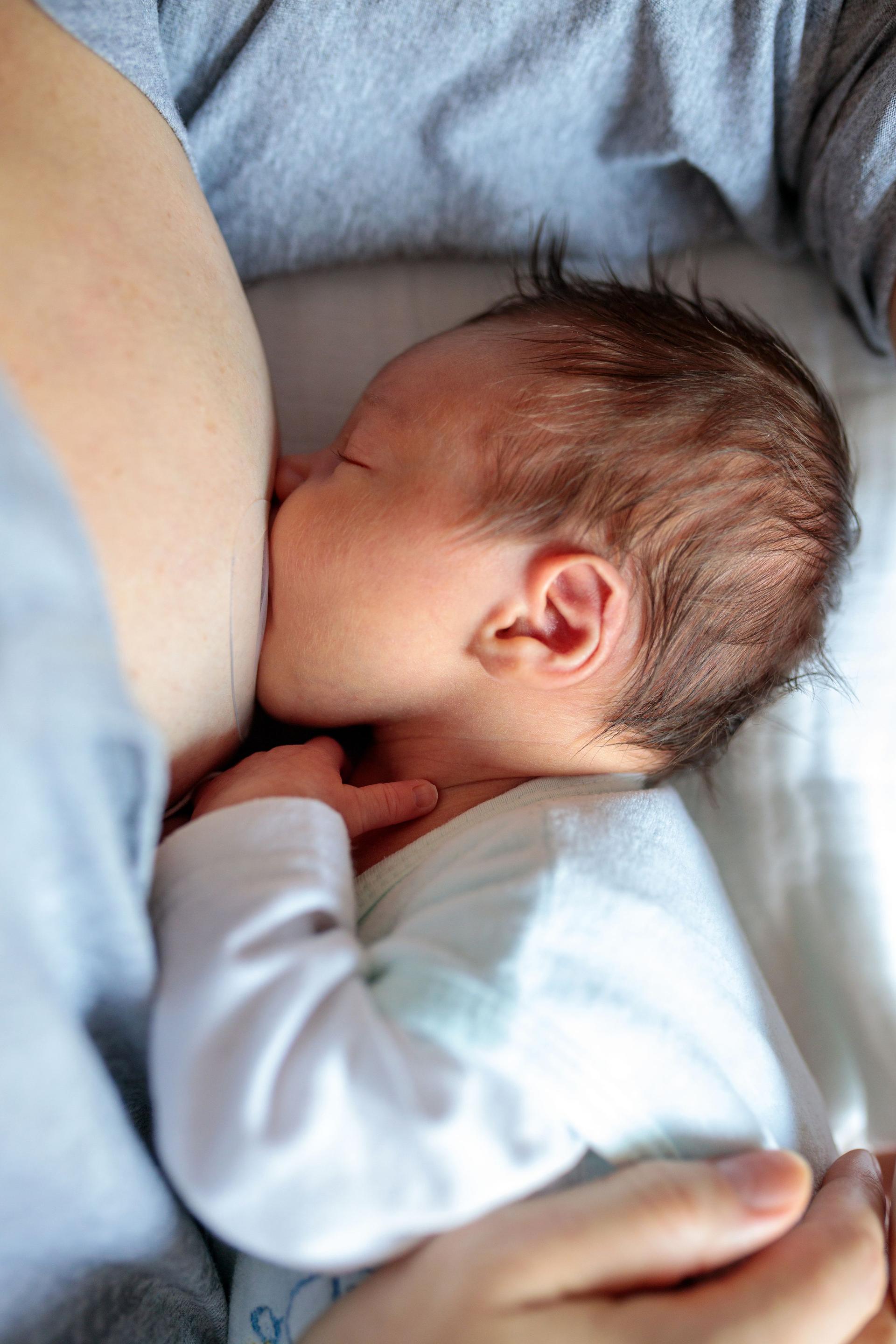 Newborn baby sucking milk from mother's breast