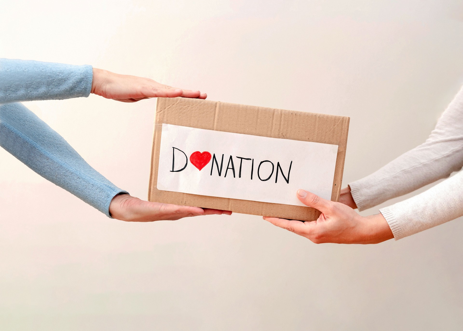 Close up of Volunteers giving donation cardboard box with love symbol,charity and support concept